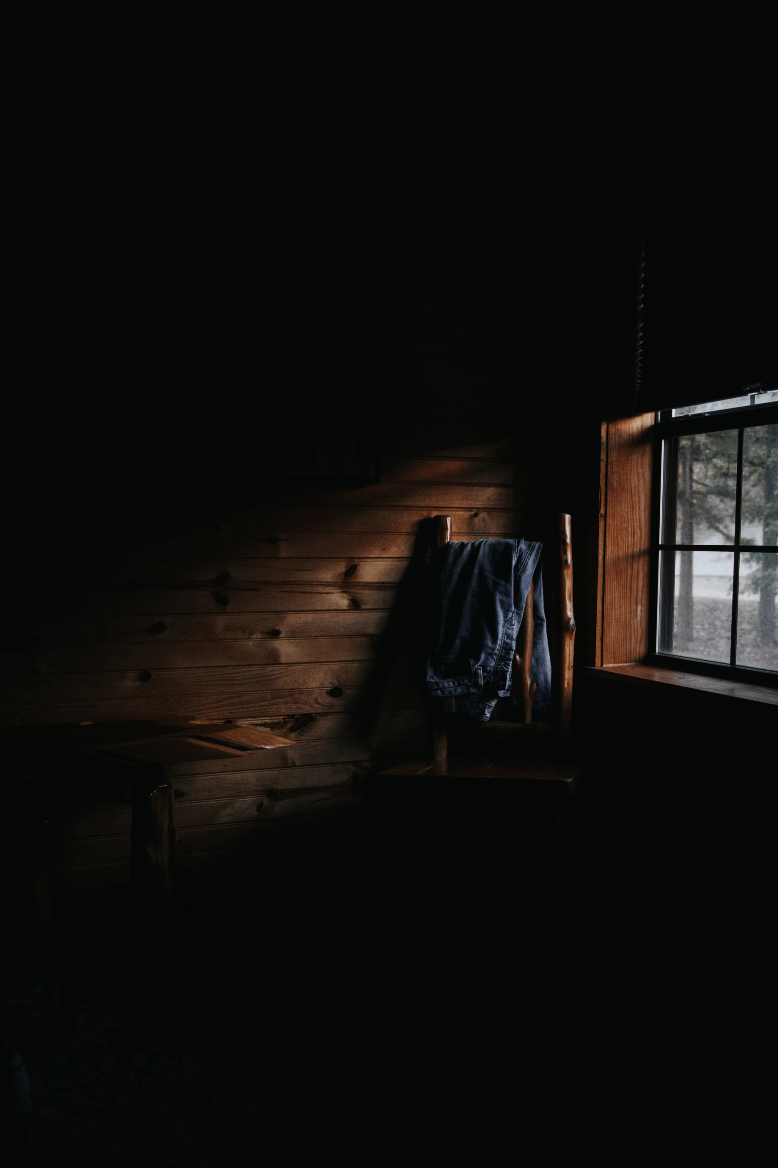an open window sitting next to a wooden bench in a dark room