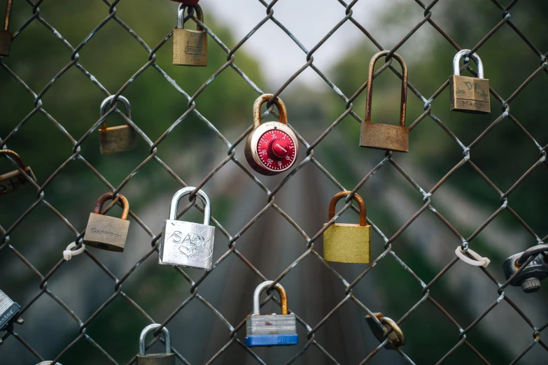 many padlocks are on a metal fence with keys attached