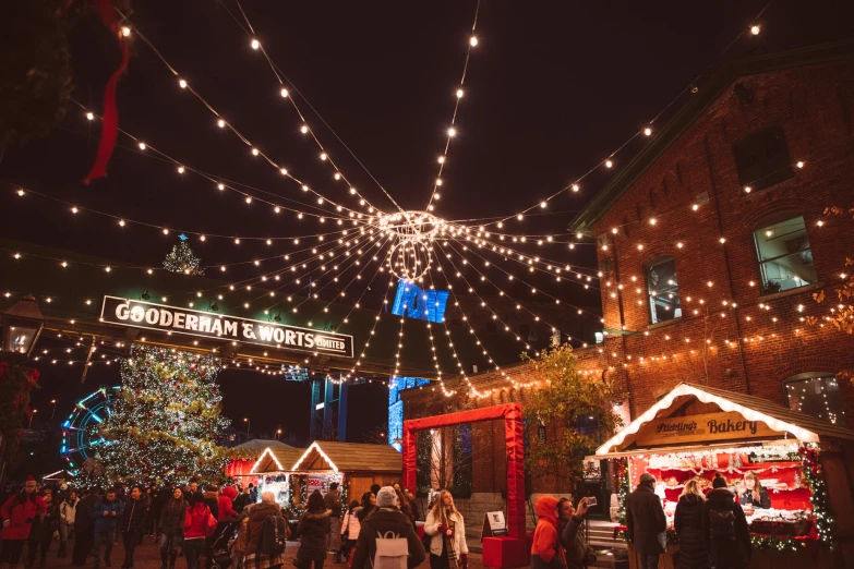 an outdoor city market with christmas lights hanging