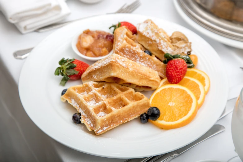 a plate of waffles with fruit and syrup on it