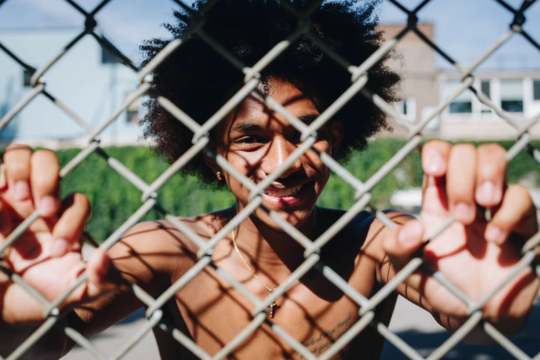 a man behind a chain link fence making the okay gesture