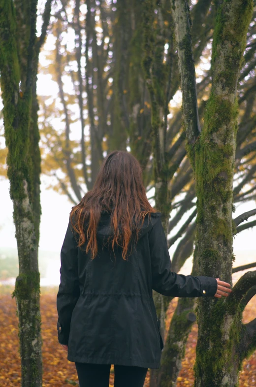 woman in parka walking away from trees