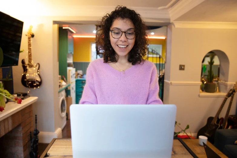 a woman wearing glasses, sitting in front of a laptop