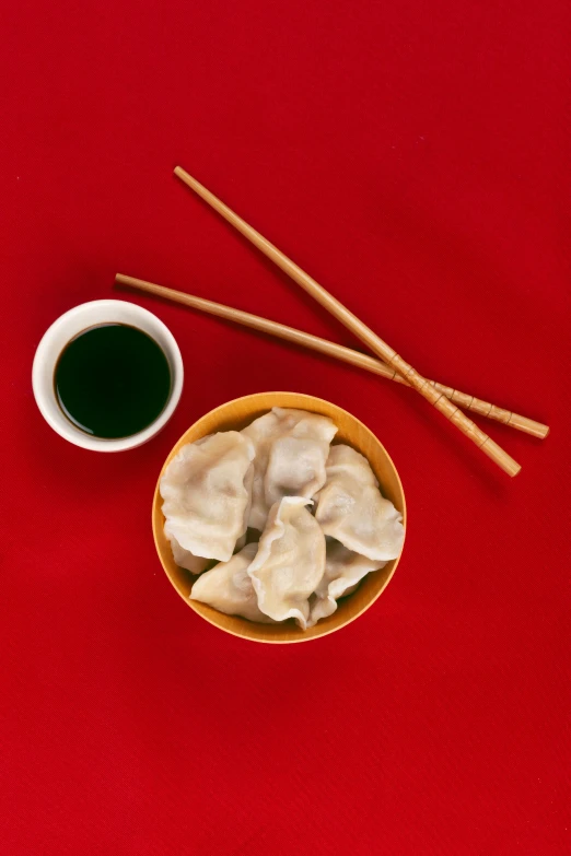 a plate of dumplings next to chopsticks and cup of tea