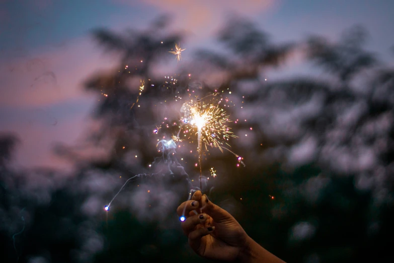 a person holds a sparkler up to the sky