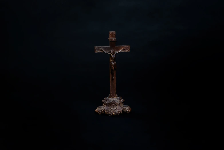 a wooden cross and a black background with only a light on