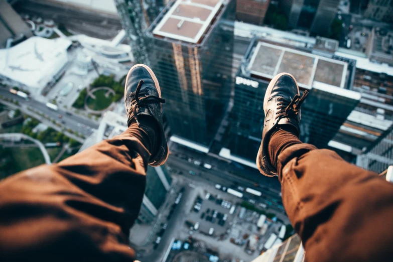 feet with jeans on standing on a ledge in front of a cityscape