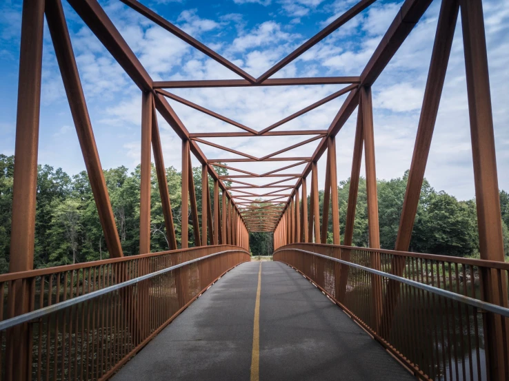 a narrow metal bridge spanning over a lake