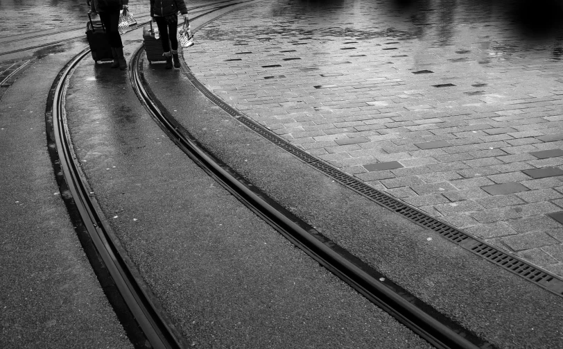 the two people walk down the tracks near the street