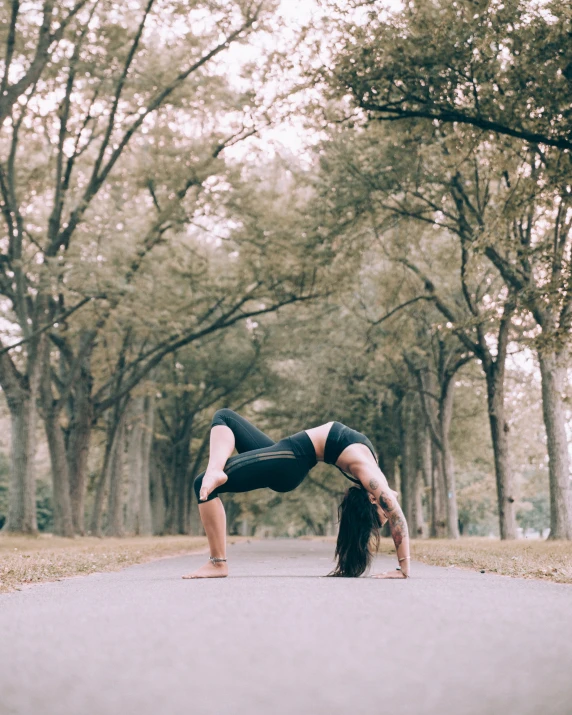 a woman is doing a yoga pose in the middle of the road