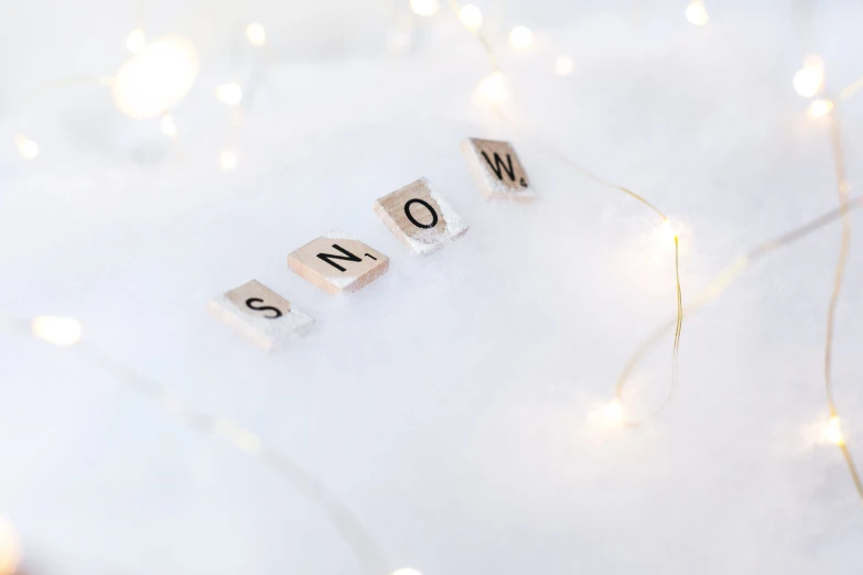 word snow spelled with small wooden blocks in white winter background