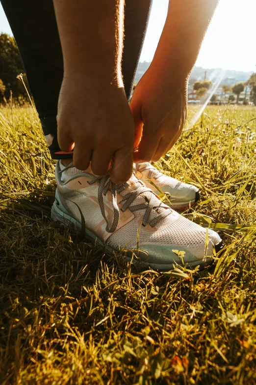 the person tying the shoelaces on his tennis shoe