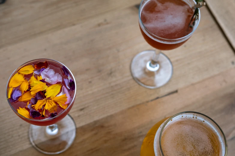 three different drink types in glasses on top of a wooden table