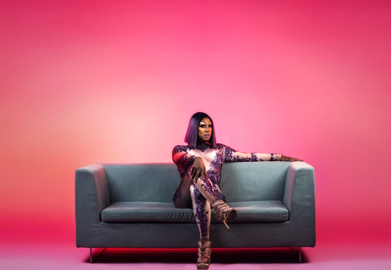 a woman sitting on a couch with a pink and purple background