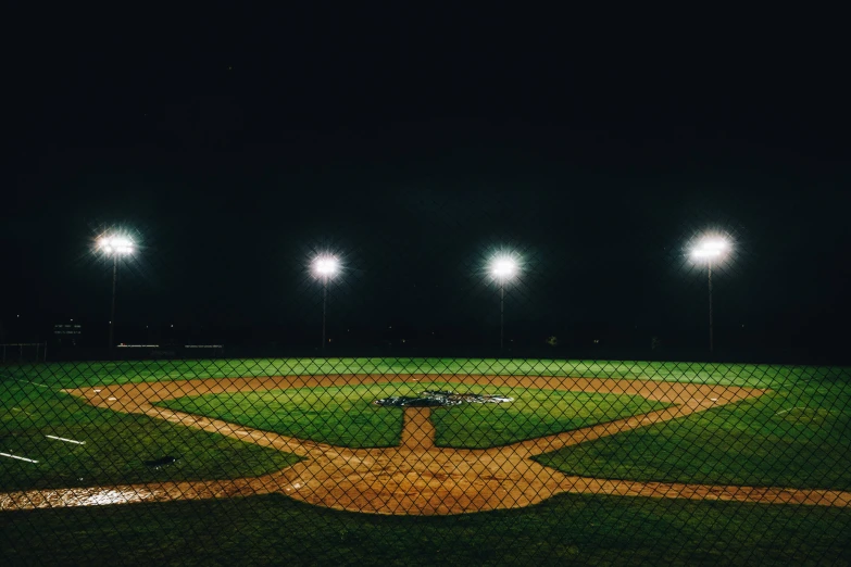 an empty baseball field with a batter at the plate and many lights on