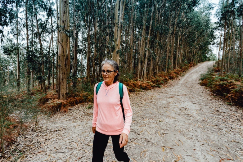 an elderly woman riding her skateboard down a dirt road