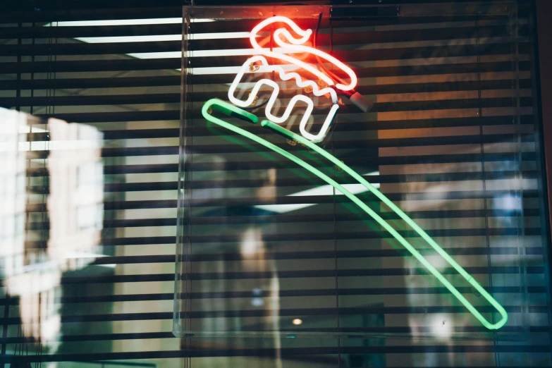 a neon sign hangs behind blinds on a window