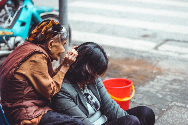 a woman sitting next to a man on a city sidewalk