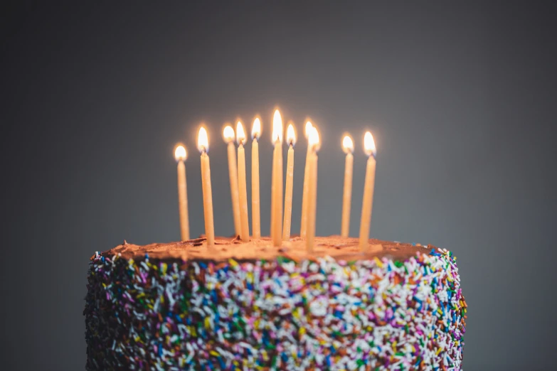 this colorful birthday cake has lit candles in the middle