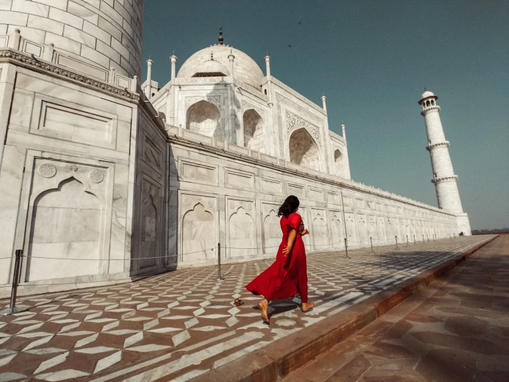 a woman in red in front of an architectural structure