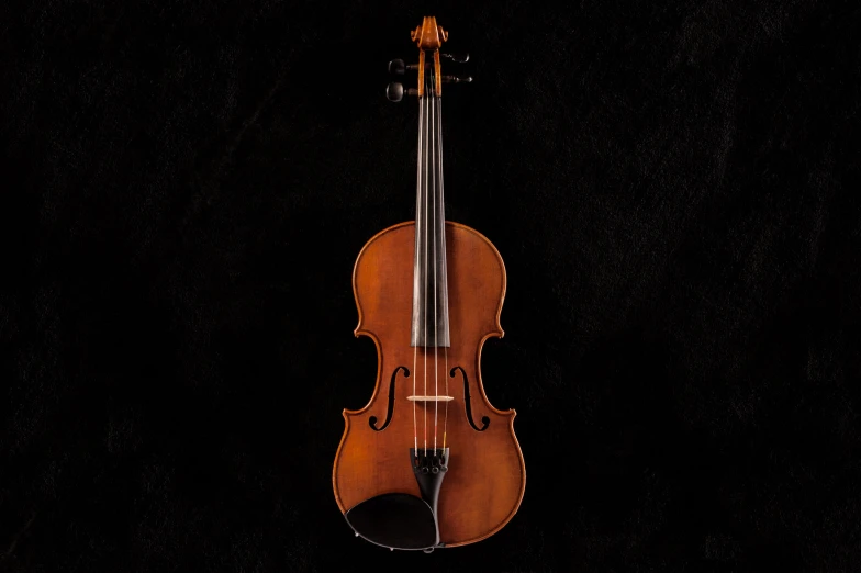 the bottom view of an antique violin against a black background