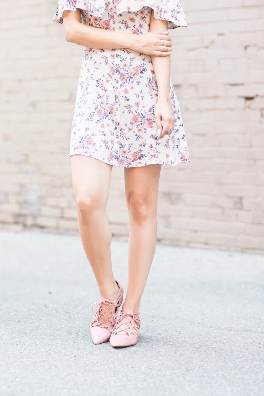 a woman in pink shoes and a flowery dress