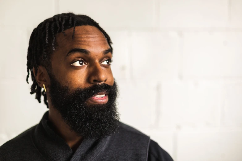 a bearded man wearing a grey shirt looking up at the camera