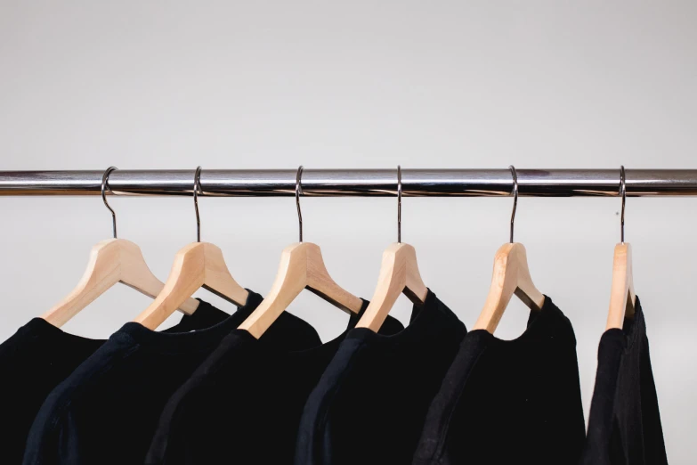 three dark shirt hanging on a metal rod