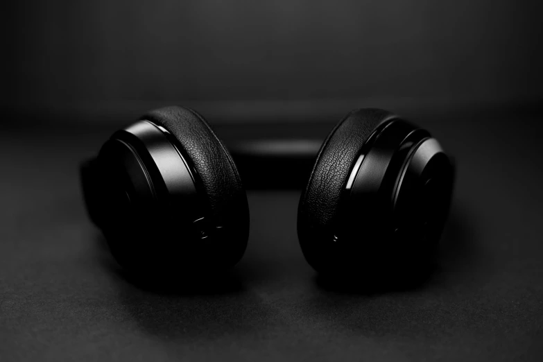 a black pair of headphones sits on a black surface