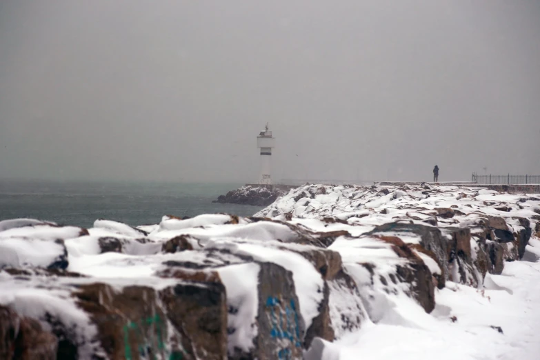 the ocean is covered in snow with a light house visible