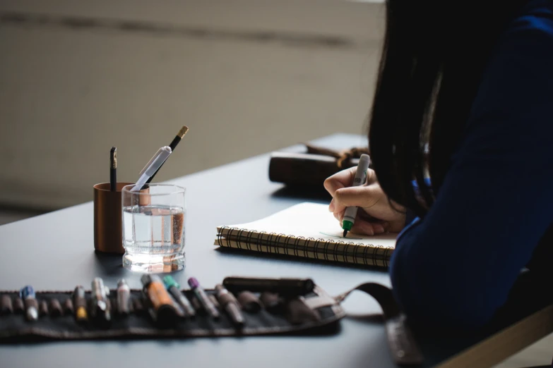 a woman's hand and glass of water on a desk