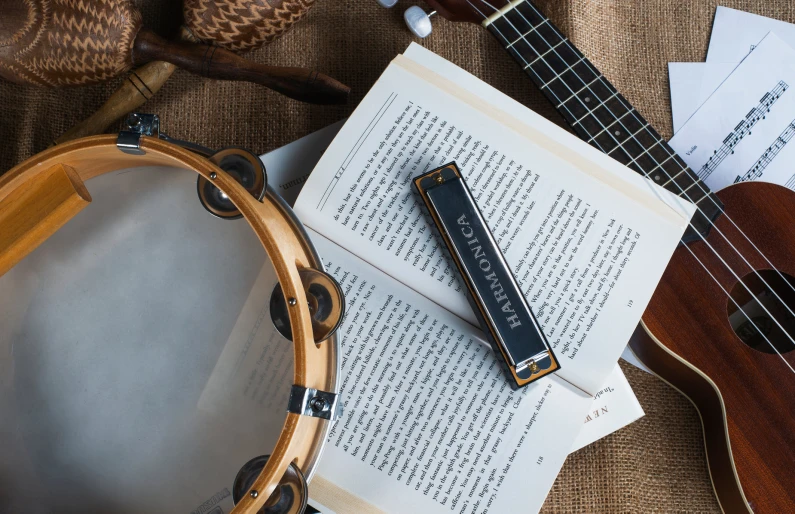 an open book, guitar and drum on a blanket