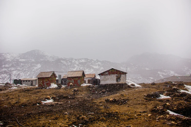 two old houses sitting on top of a hill with mountains in the background