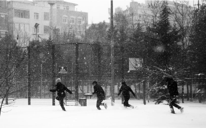 several people are walking through the snow near fenced off areas