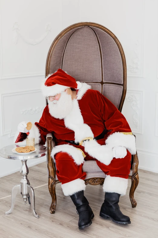 a santa clause sitting on a chair eating a dessert
