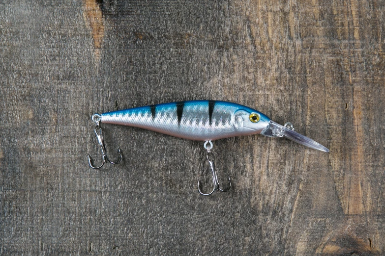 a blue - eyed fishing spoon on a chain hanging off a wooden wall