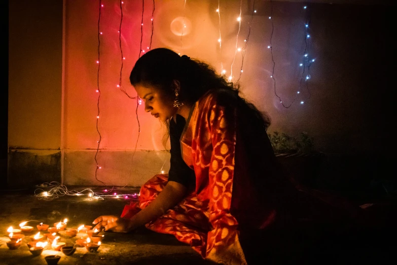 woman sitting on floor by candles in room