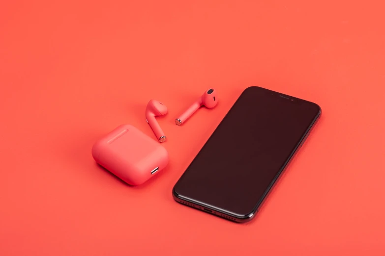 a black cellphone with a pink ear buds near it