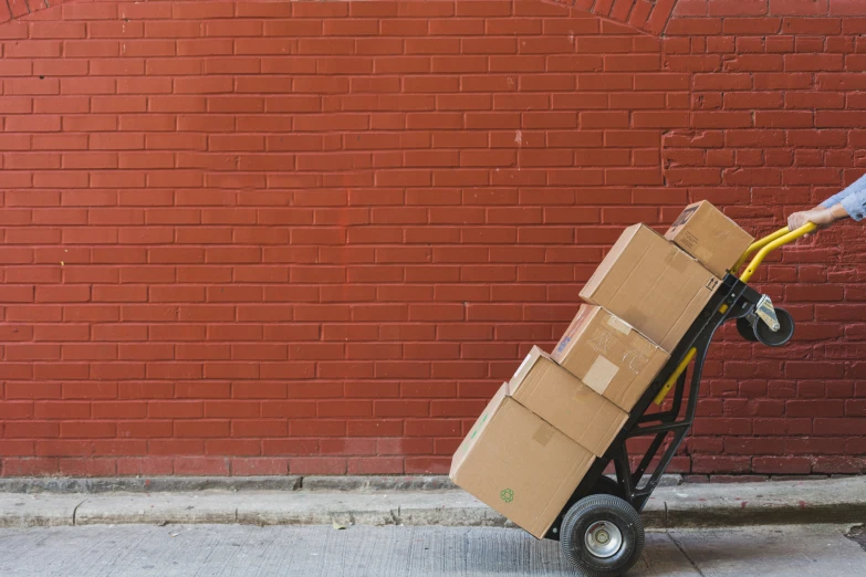 a person pulling a hand cart with boxes on it