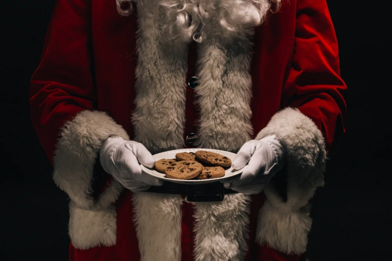 santa claus holding a plate of cookies in his hands