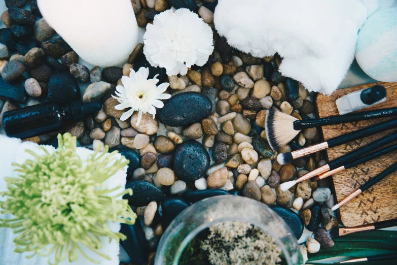 a flower, pens, brushes and other items are sitting on a pile of rocks