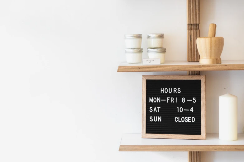 two shelves with candles and a sign