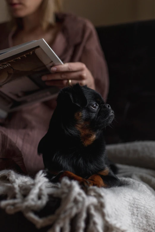 a woman is reading a book with her dog