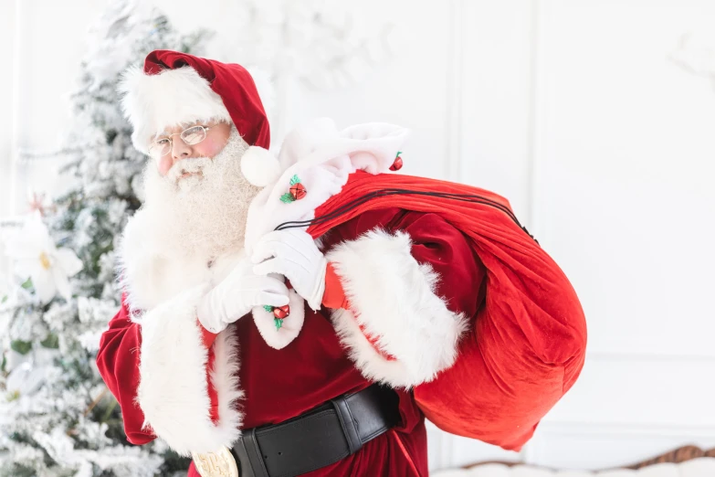 santa clause dressed in red with white hair holding onto a backpack