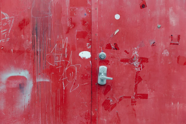 a red door with graffiti and a white door handle