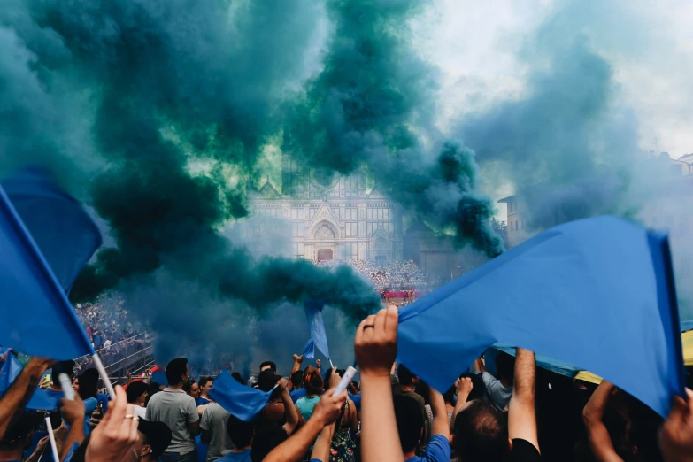 a crowd of people holding flags in front of smoke