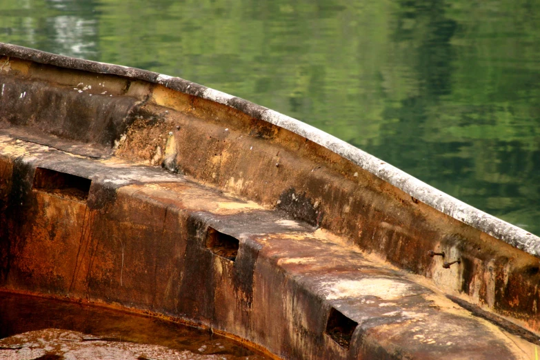the side of a wooden canoe on top of water