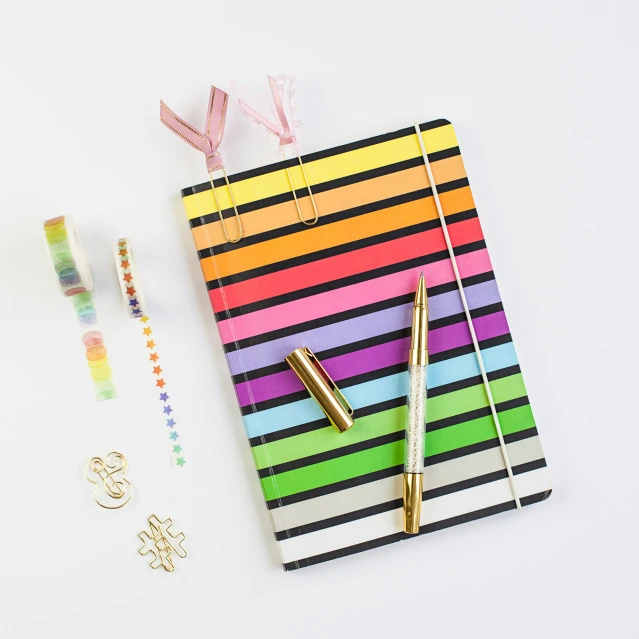 a striped notebook and a pen with a gold nose pin