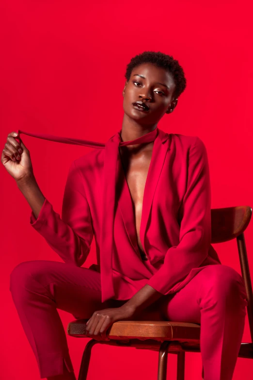 an african american model in a red suit sits on a chair