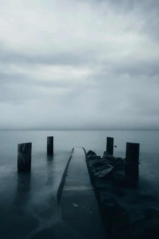 dark clouds loom above a pier and calm ocean